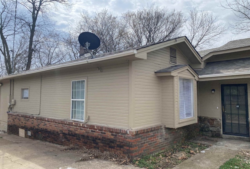 View of home's exterior with a shingled roof and brick siding