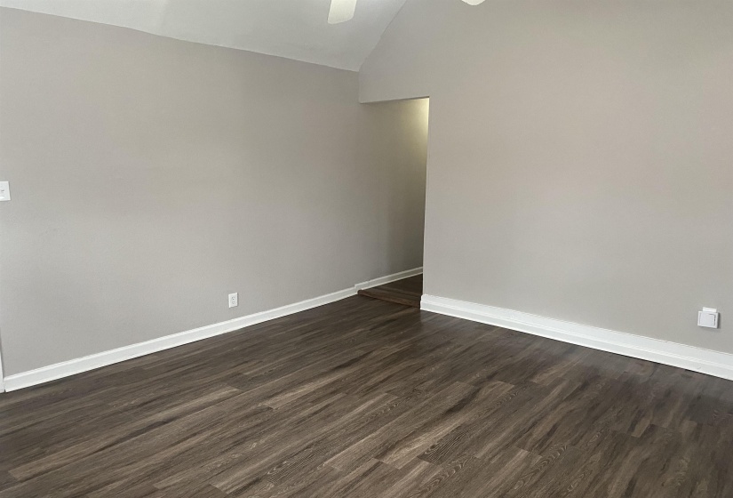 Spare room with dark wood finished floors and vaulted ceiling