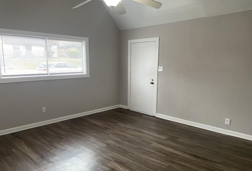 Spare room with dark wood finished floors, vaulted ceiling, and a ceiling fan