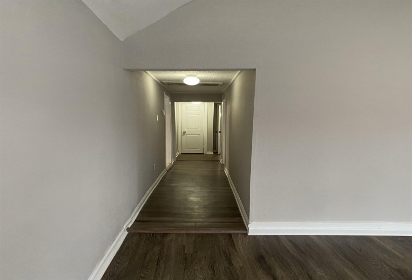 Corridor with lofted ceiling and dark wood-style flooring