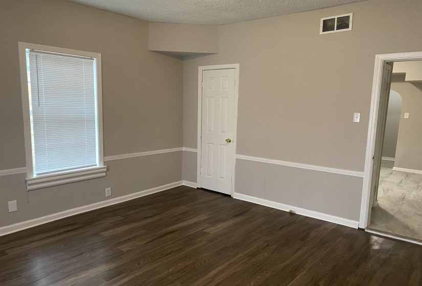 Spare room featuring a textured ceiling, dark wood finished floors, and arched walkways