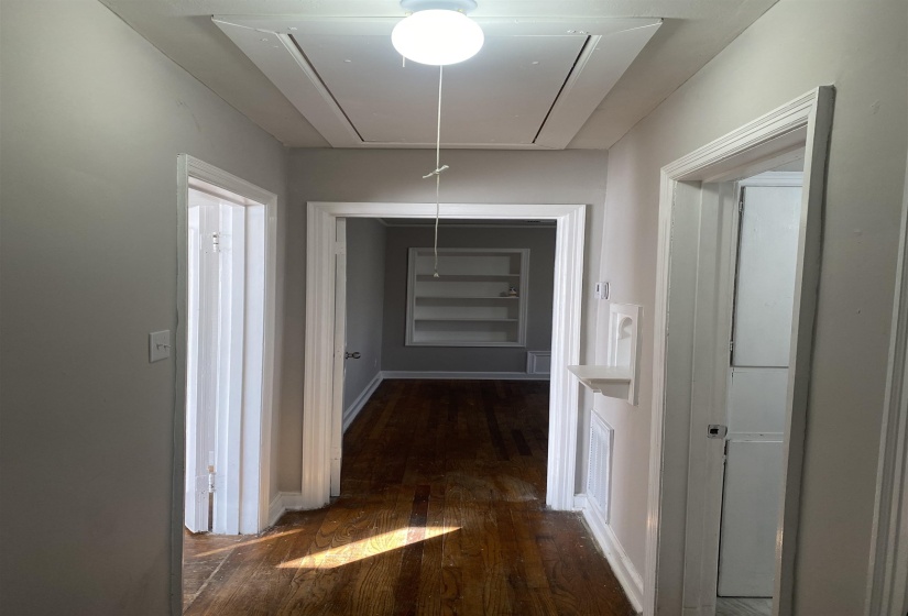 Corridor featuring cooling unit, attic access, and dark wood-style flooring