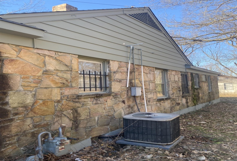 Exterior view of stone siding and a cooling unit