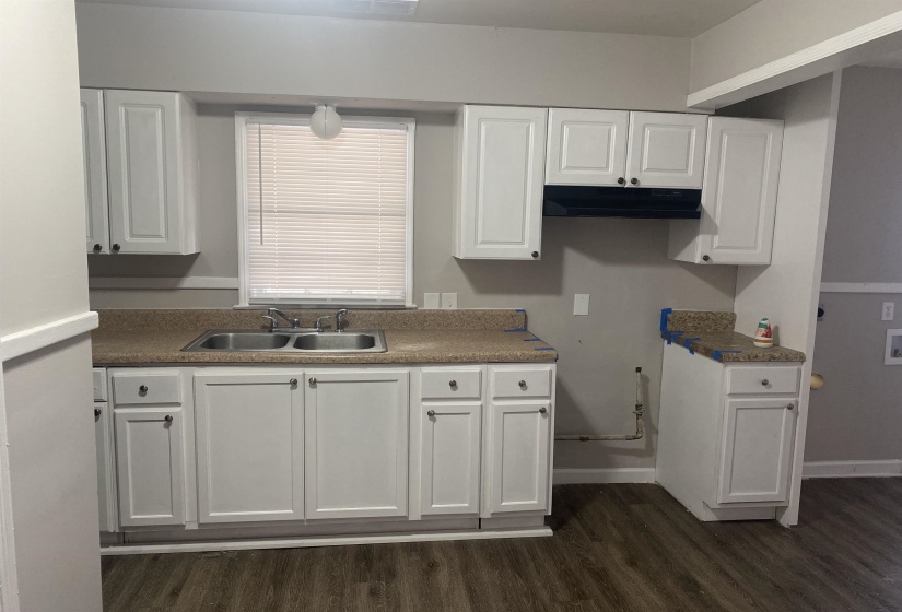 Kitchen featuring white cabinetry, dark wood finished floors, dark countertops, and under cabinet range hood