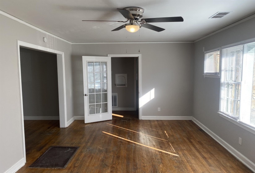 Spare room featuring dark wood finished floors, crown molding, and ceiling fan