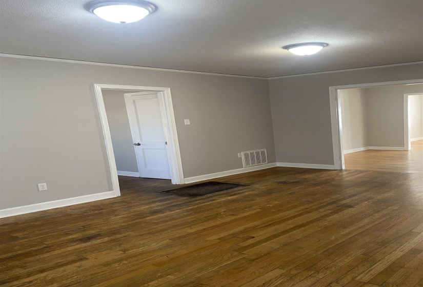 Unfurnished room with dark wood-style floors, ornamental molding, and a textured ceiling