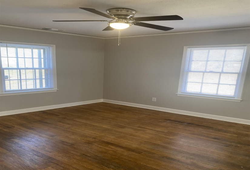 Unfurnished room with dark wood-type flooring, crown molding, and ceiling fan