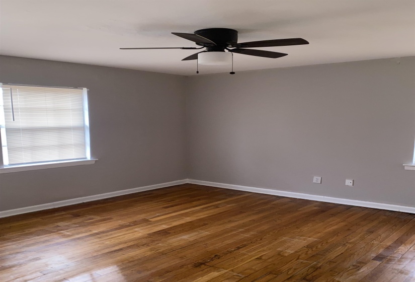 Empty room featuring dark wood-type flooring and ceiling fan