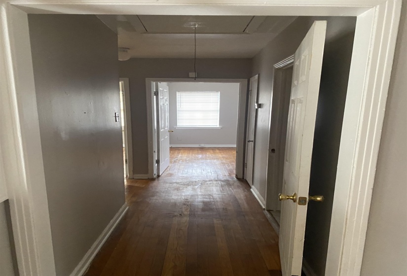 Hall featuring attic access and dark wood-style flooring