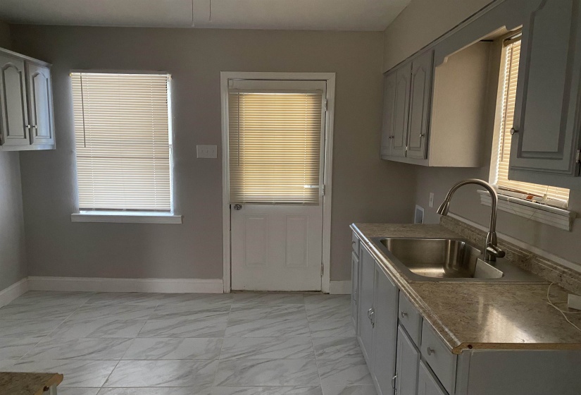 Kitchen with light marble finish floors, light countertops, gray cabinetry, and plenty of natural light