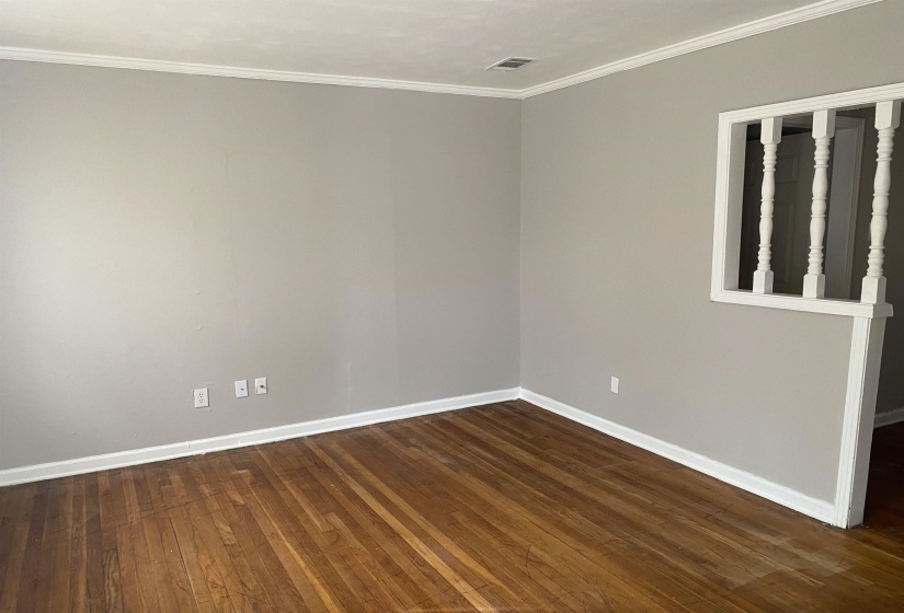 Spare room featuring dark wood finished floors and crown molding