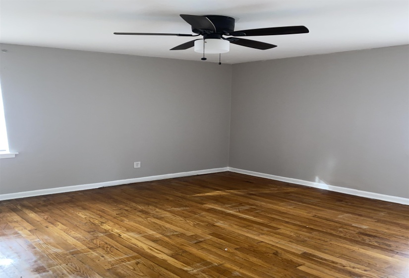 Empty room with dark wood finished floors and a ceiling fan