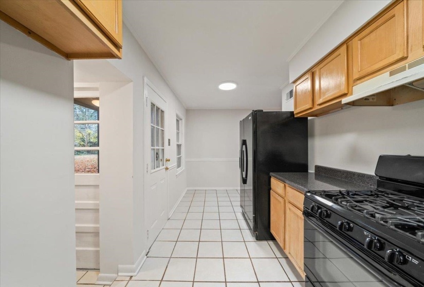 Kitchen featuring black appliances, light tile patterned floors, and under cabinet range hood