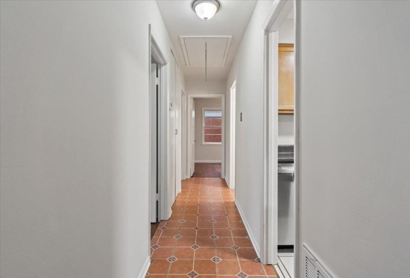 Hallway with attic access and light tile patterned floors