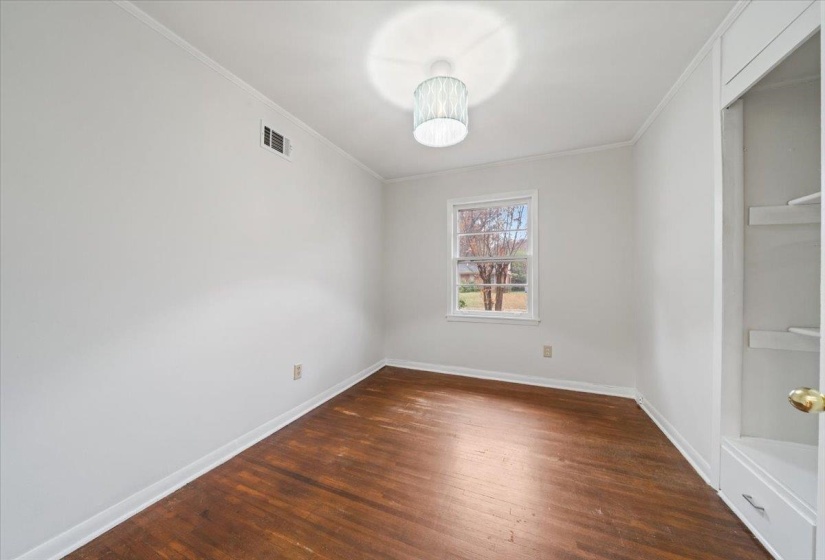 Empty room featuring crown molding and dark wood-style flooring