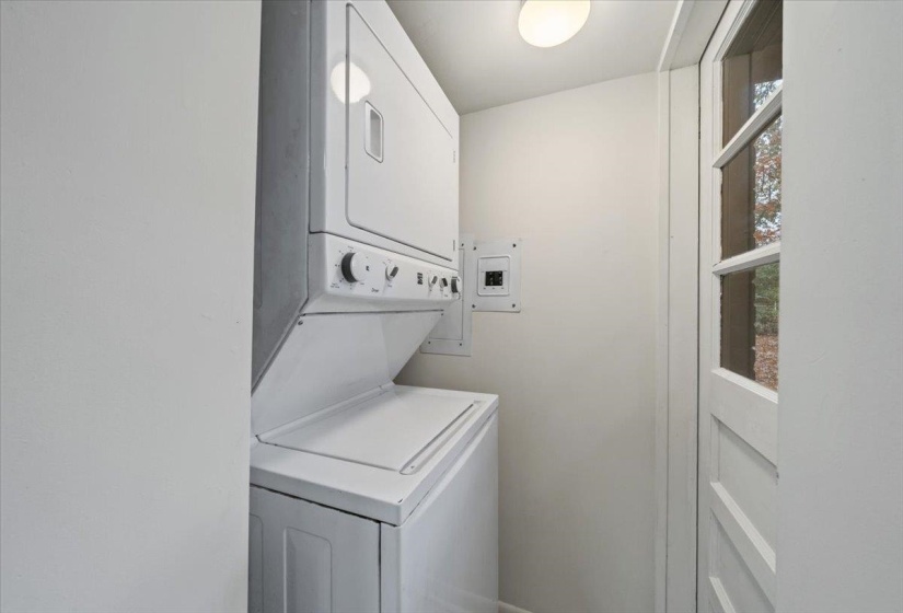 Laundry area featuring stacked washer / dryer and electric panel