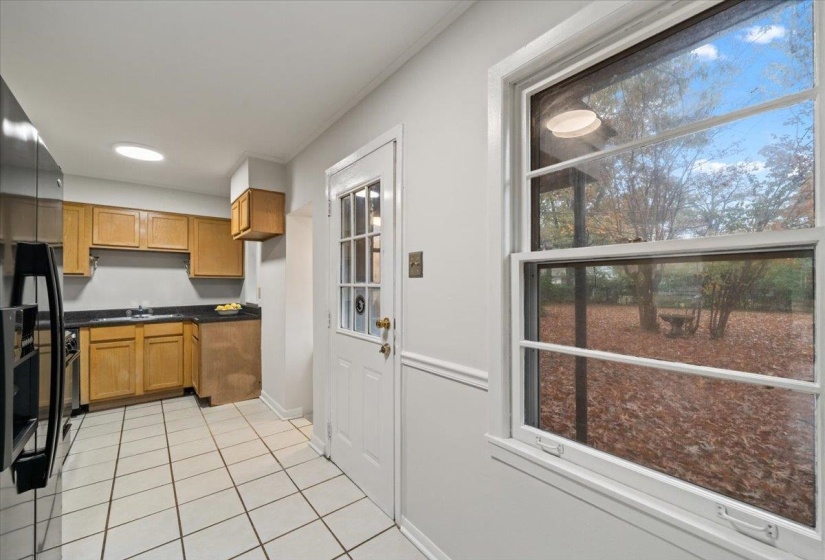 Kitchen featuring dark countertops, black appliances, light tile patterned floors, and brown cabinets