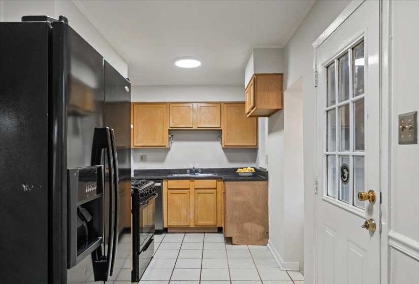 Kitchen with black appliances, brown cabinets, and light tile patterned flooring
