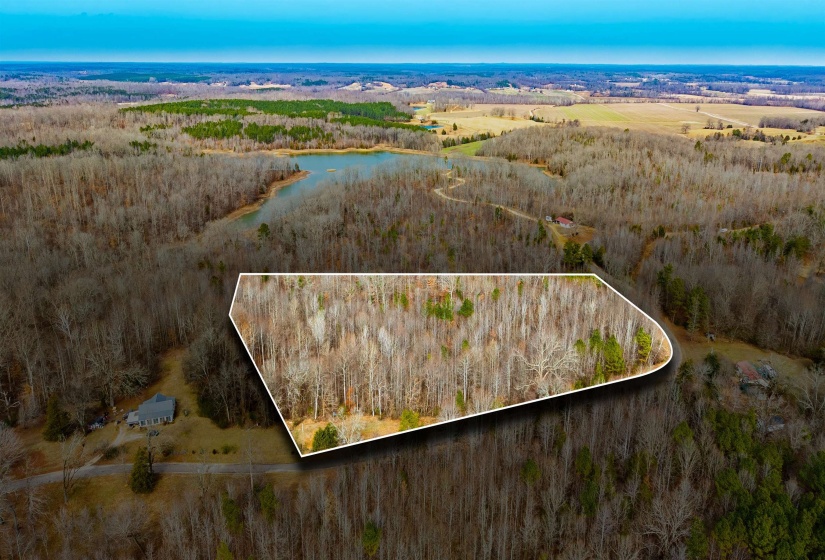 Aerial overview of property's location with a heavily wooded area and property parcel outlined