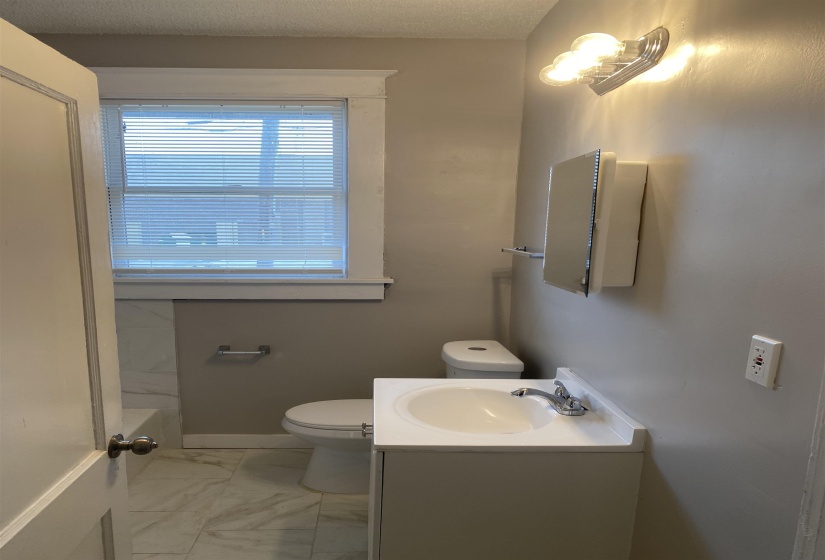 Bathroom featuring vanity, light marble finish floors, a tub, and a textured ceiling