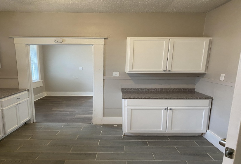 Kitchen with white cabinetry, wood finish floors, and a textured ceiling