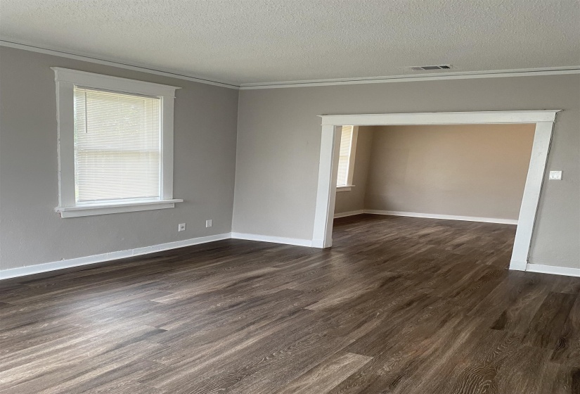 Unfurnished room featuring a textured ceiling, dark wood finished floors, and crown molding