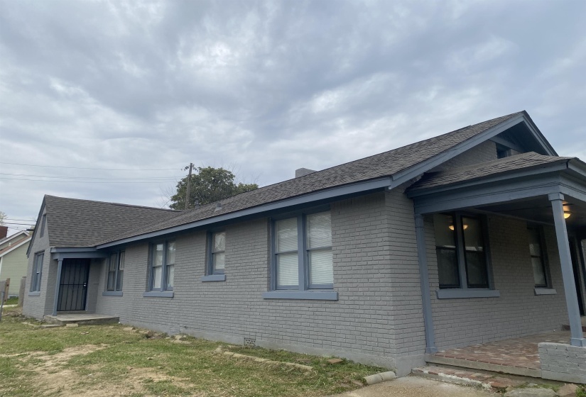 View of side of home with brick siding and roof with shingles