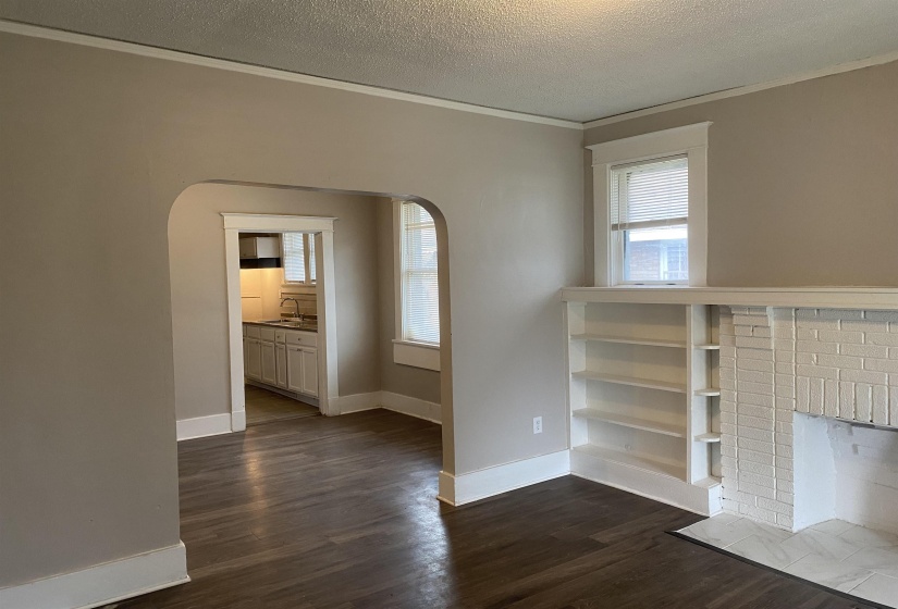 Spare room featuring dark wood-style floors, a textured ceiling, ornamental molding, arched walkways, and plenty of natural light