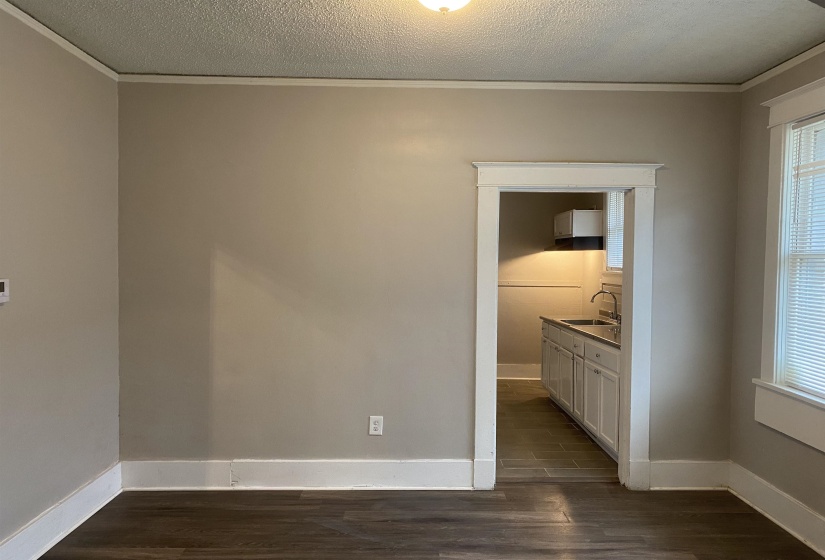 Unfurnished bedroom with dark wood-style flooring, a textured ceiling, ornamental molding, and connected bathroom