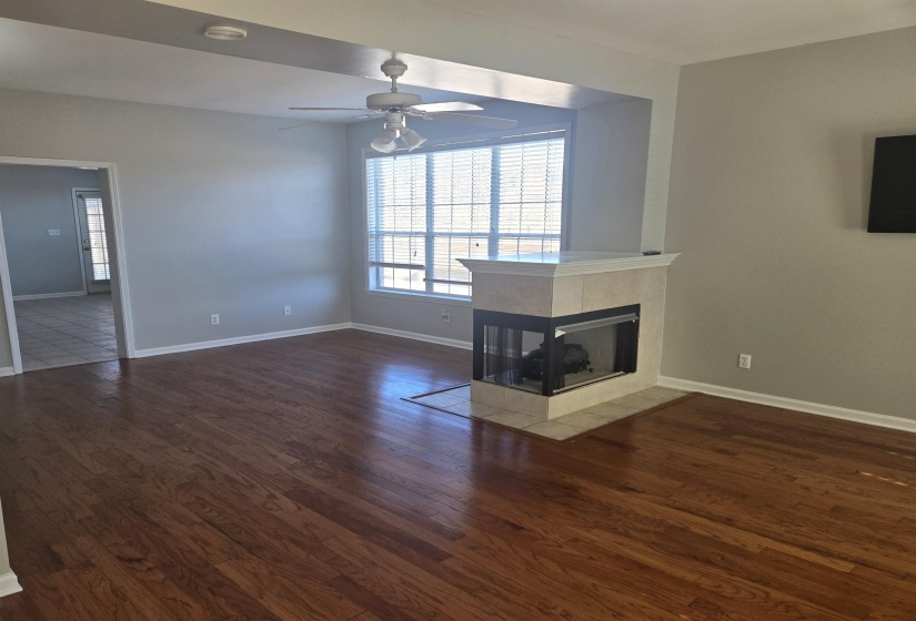 Unfurnished living room with a tile fireplace, dark wood-type flooring, and ceiling fan