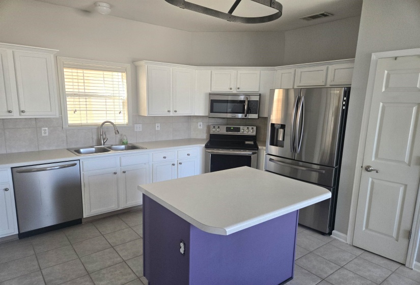 Kitchen featuring white cabinets, stainless steel appliances, light tile patterned floors, and light countertops