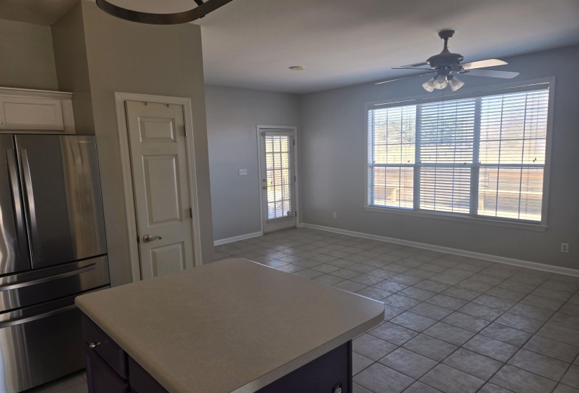 Kitchen with freestanding refrigerator, light countertops, light tile patterned floors, a ceiling fan, and a center island