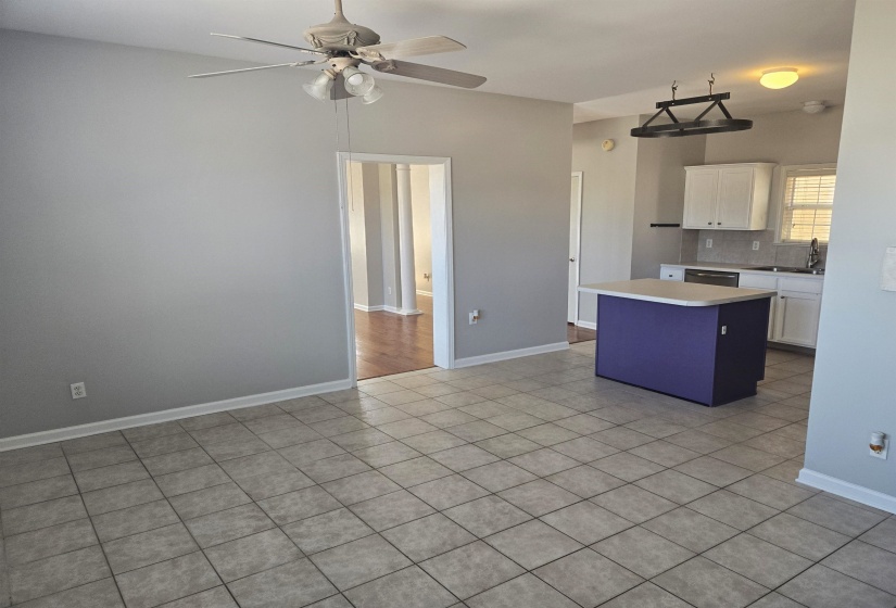 Kitchen featuring white cabinets, a kitchen island, decorative backsplash, light countertops, and light tile patterned floors