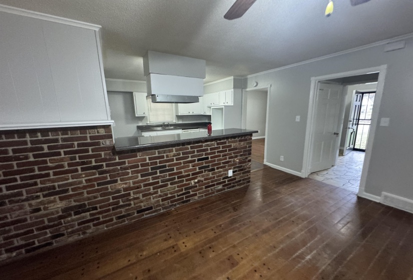 Kitchen with a peninsula, dark countertops, a ceiling fan, dark wood-style floors, and white cabinetry