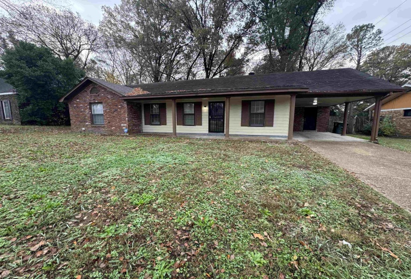 Single story home featuring a front yard, a carport, a porch, and concrete driveway