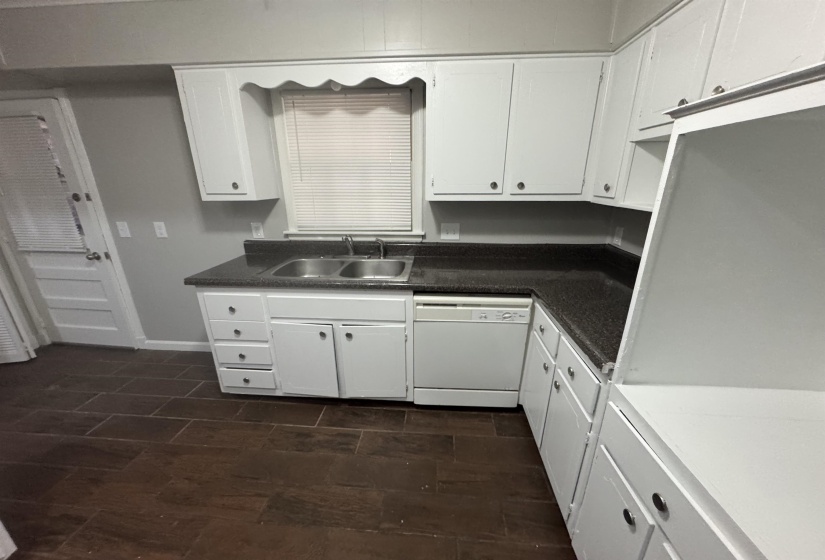 Kitchen featuring white cabinetry, dishwasher, and wood tiled floors
