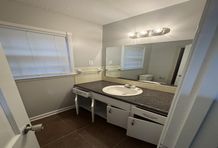 Half bathroom featuring dark tile patterned flooring, vanity, and a textured ceiling