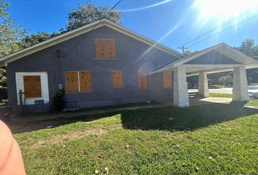 View of side of property featuring a lawn, brick siding, and a patio