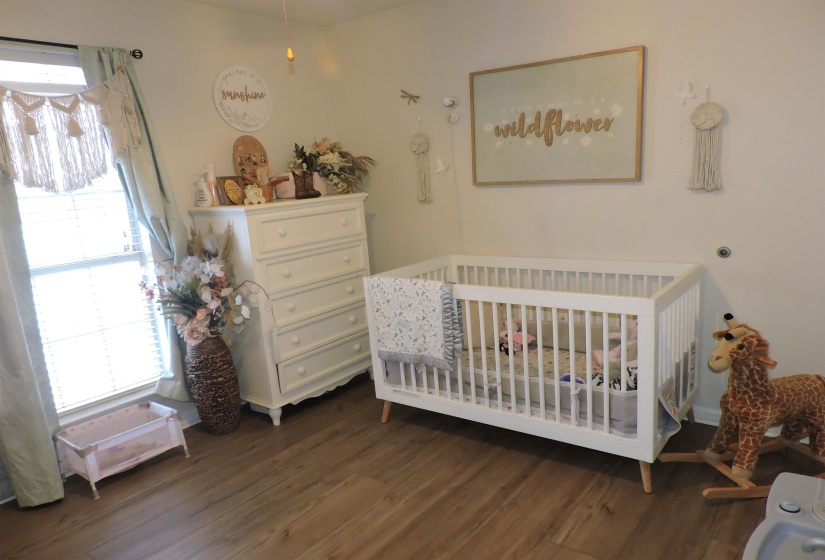 Bedroom with a nursery area and dark wood-style floors
