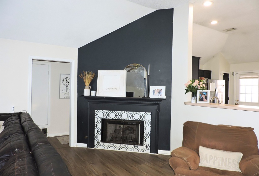 Living room featuring vaulted ceiling, wood finished floors, and a fireplace