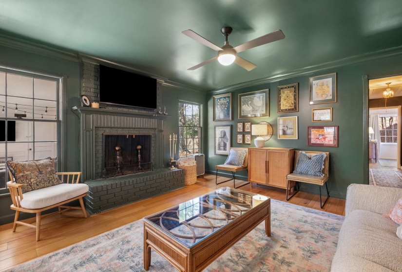 Living area with crown molding, hardwood / wood-style flooring, a fireplace, and a ceiling fan
