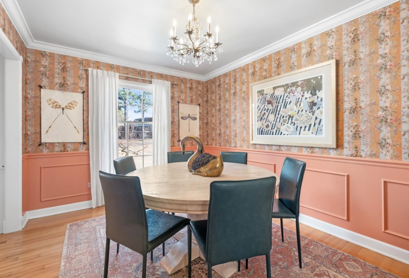 Dining room with a wainscoted wall, wallpapered walls, a decorative wall, crown molding, and a chandelier