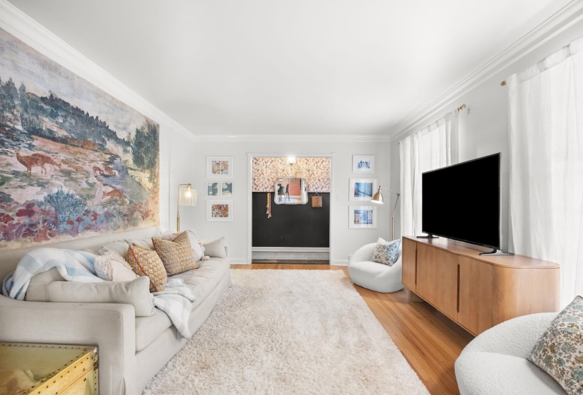 Living area with wood finished floors and ornamental molding