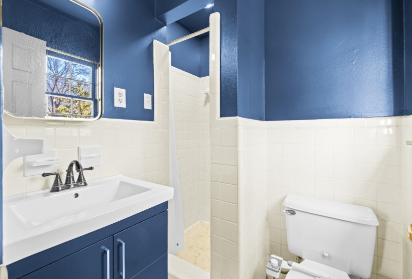 Full bath with a stall shower, vanity, tile walls, wainscoting, and a textured wall