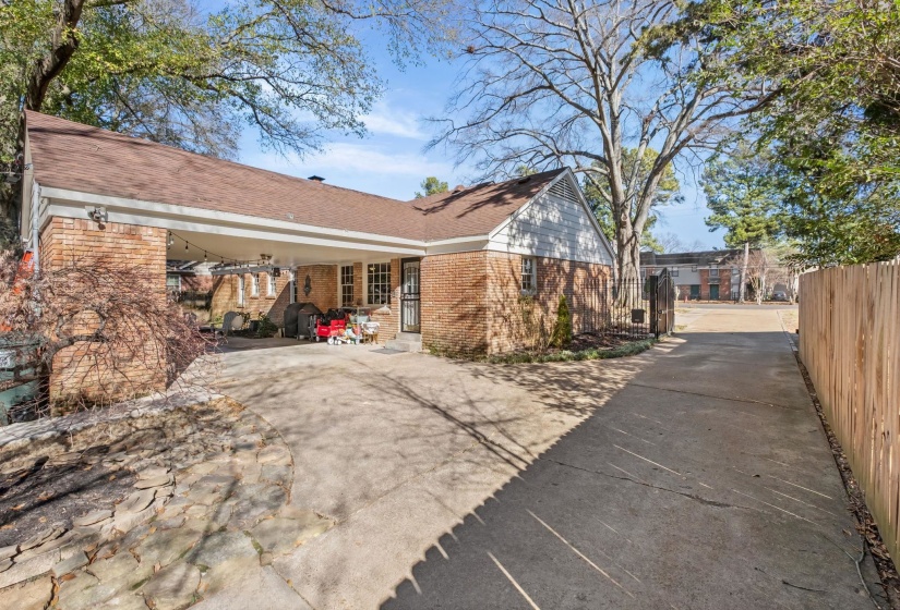 View of property exterior with brick siding, a patio area, concrete driveway, and a shingled roof