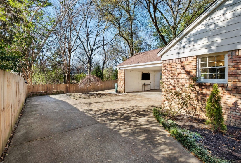 Fenced backyard featuring concrete driveway, a carport, and a patio