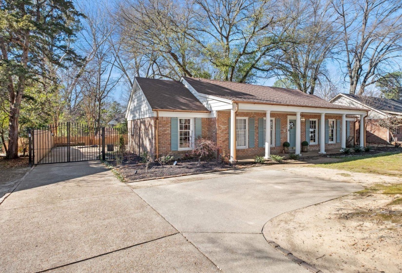 View of front facade featuring a gate, covered porch, brick siding, and concrete driveway