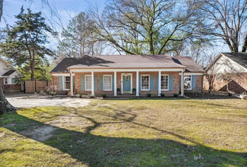 View of front of home with a porch, brick siding, and roof with shingles