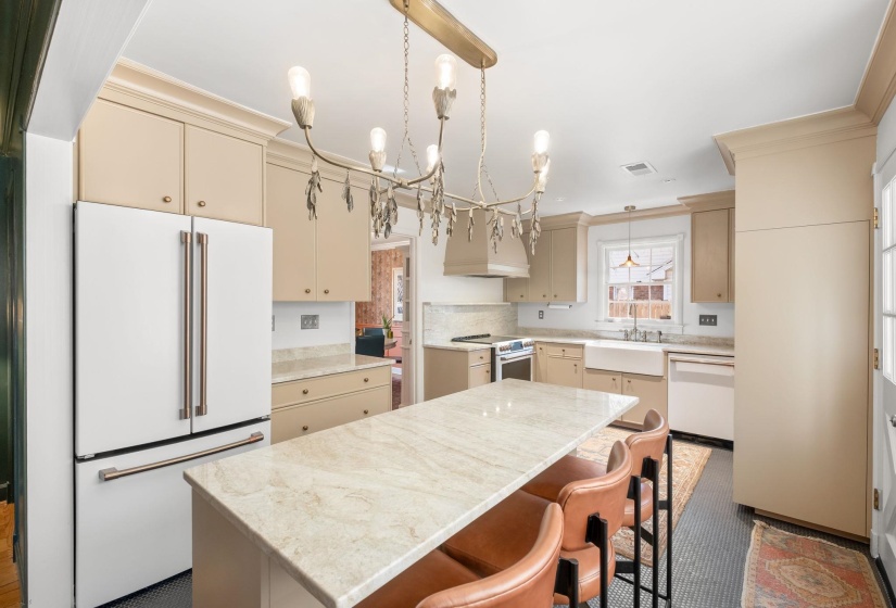 Kitchen with cream cabinetry, white appliances, pendant lighting, a kitchen island, and crown molding