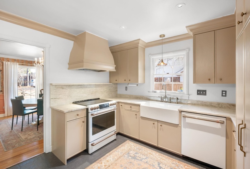 Kitchen with cream cabinets, white appliances, premium range hood, decorative light fixtures, and crown molding